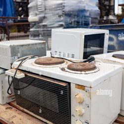 old broken small hot plate oven and other old e waste appliances pilled up in the background 2kykpa1