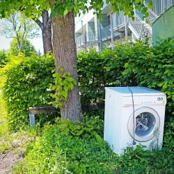 washing machine dumped as garbage abandoned sidewalk sharply contrasting green environment washing machine 189142797